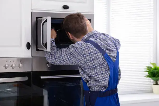 Oven repair technician fixing a built-in oven in Philadelphia PA