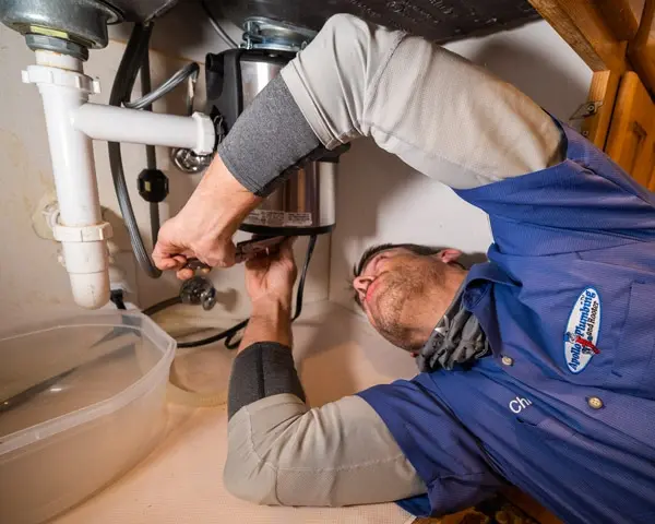 Technician replacing a garbage disposal under a kitchen sink in Philadelphia