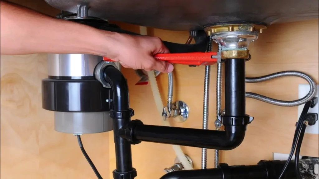 Technician repairing a garbage disposal under a kitchen sink in Philadelphia